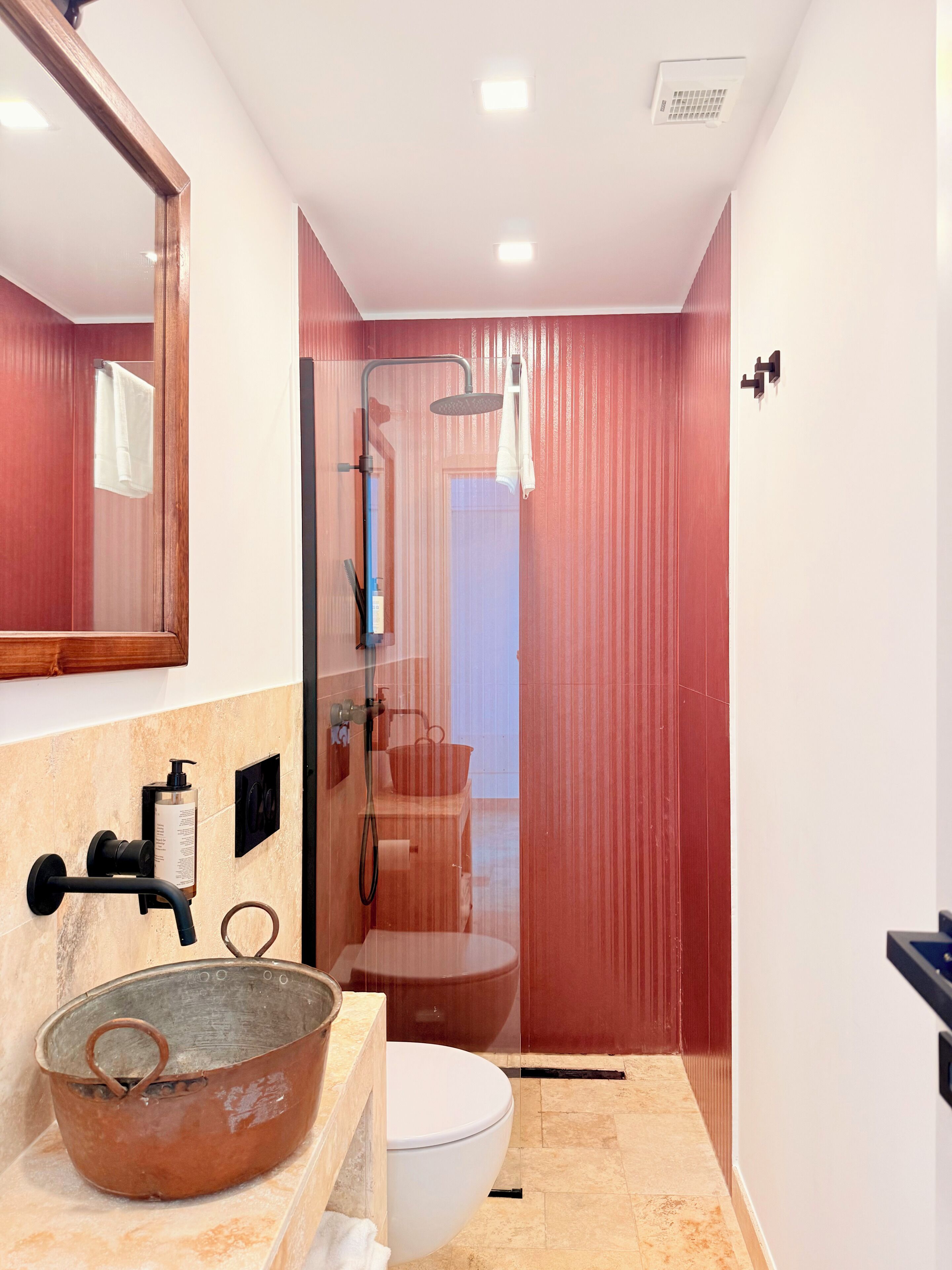 A bathroom with a shower, toilet, and a large basin.