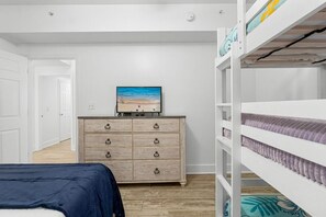 Ein Schlafzimmer mit einem Bett, einer Kommode, einem Fernseher und Etagenbetten.