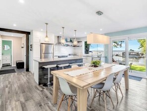 A modern kitchen with a central island, pendant lights, and a view of the outdoors.