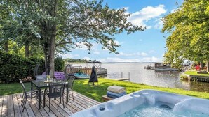 Eine Terrasse mit Whirlpool, einem Tisch und Stühlen sowie Blick auf einen See.