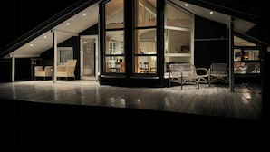 Ein modernes Haus mit Satteldach, großen Fenstern und einer Holzterrasse.