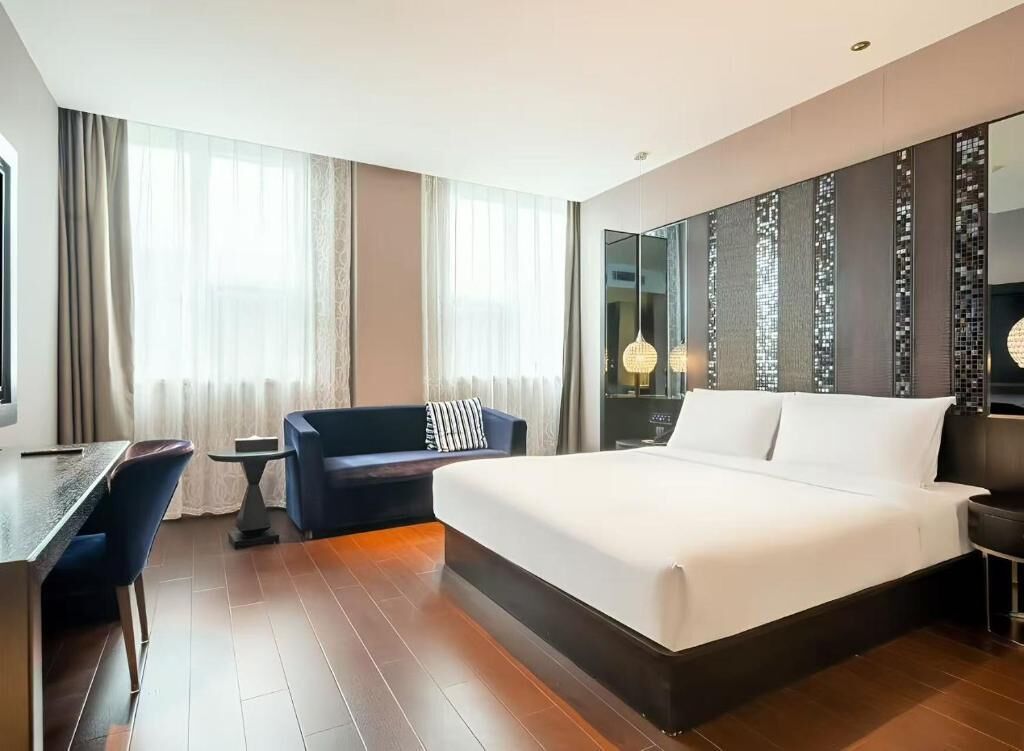 Una habitación de hotel con una cama grande, un escritorio, una silla y un sofá.