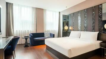 Una habitación de hotel con una cama grande, un escritorio, una silla y un sofá.