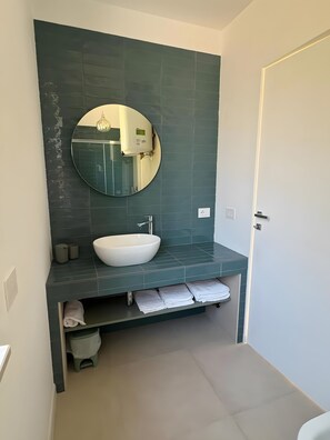 A bathroom with a white sink, a round mirror, and a towel rack.