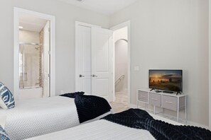 A bedroom with two beds, a TV on a white cabinet, and a bathroom visible through an open door. - Family Retreat with 4Bed suites & Private Jacuzzi (Four Corners)