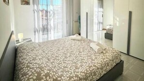 Ein modernes Schlafzimmer mit Bett, Spiegel und Blick auf die Stadt.