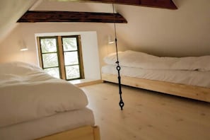 A room with a loft bed, a window with a view, and a hanging light fixture.