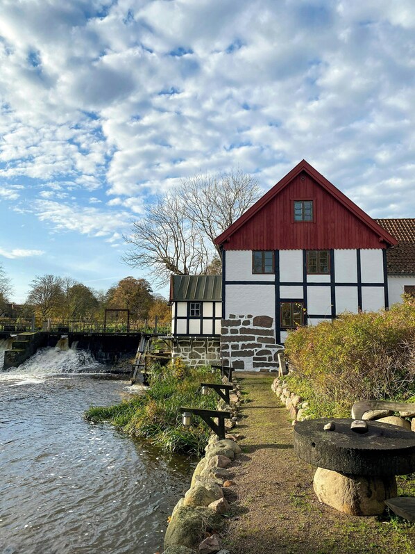 A traditional building with a red roof and white walls, located beside a flowing waterway.