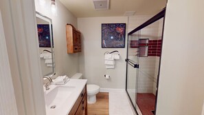 A modern bathroom with a glass shower enclosure, a wooden vanity, a white sink, and two wall-mounted towels. - NEW! Seneca 213 - Brigham One Bedroom Plus Condo (Snowshoe)