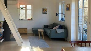 Una sala de estar con una escalera, un sofá, una mesa y una estantería.
