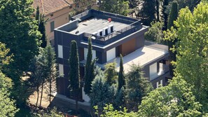 Un edificio moderno de varios pisos con techo plano, rodeado de árboles.