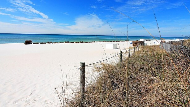 Ein Strand mit sandigem Ufer, Holzgebäuden und blauem Himmel.