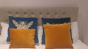 A bed with a tufted headboard, two decorative pillows, and a blue textured blanket. - Clarence House Holidays (Shanklin)