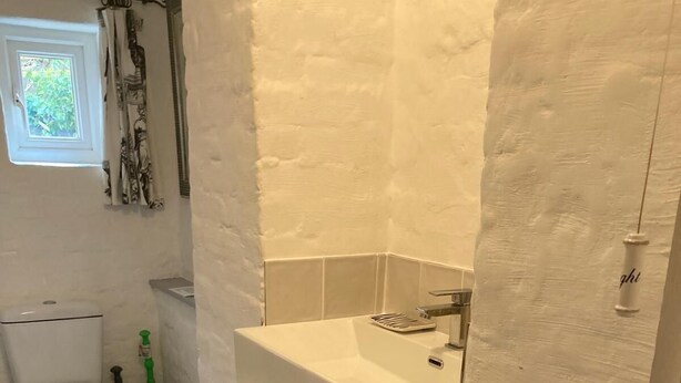 A bathroom with a toilet, a sink, and a shower curtain. - Clarence House Holidays (Shanklin)
