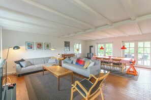 Ett vardagsrum med en soffa, ett soffbord och stolar, en tv och en matplats med ett bord och stolar.