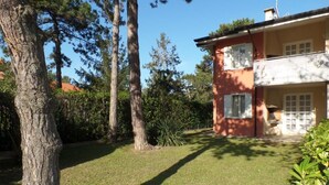 Una casa con césped cuidado, un árbol grande y una estructura de dos pisos con balcón.