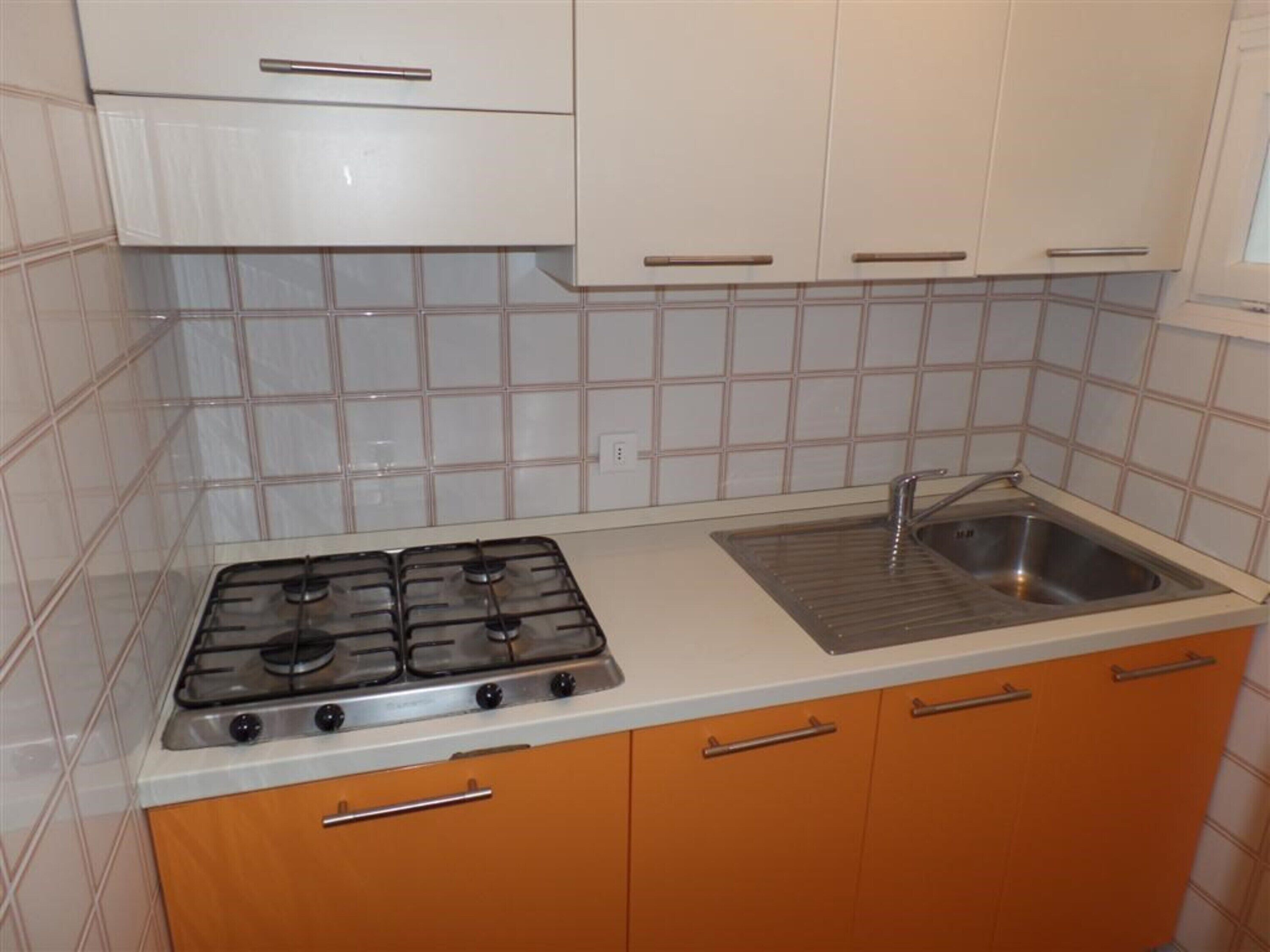 A kitchen with a gas stove, a sink, and white cabinets.