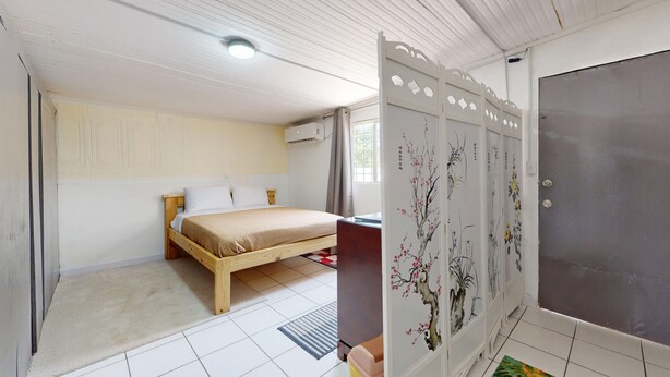 Ein Schlafzimmer mit Bett, einem Schrank mit floralem Muster und einem Fenster.