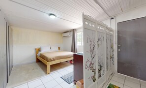 A bedroom with a bed, a wardrobe with floral designs, and a window. - Cozy apartment (Oranjestad)