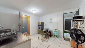 A compact living space with a kitchenette, a dining area with a table and chairs, a refrigerator, a fan, and a window. - Cozy apartment (Oranjestad)