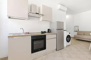 Cocina compacta con horno integrado, lavadora y refrigerador.