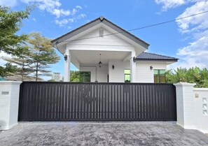 A house with a covered porch, a black gate, and a clear sky.