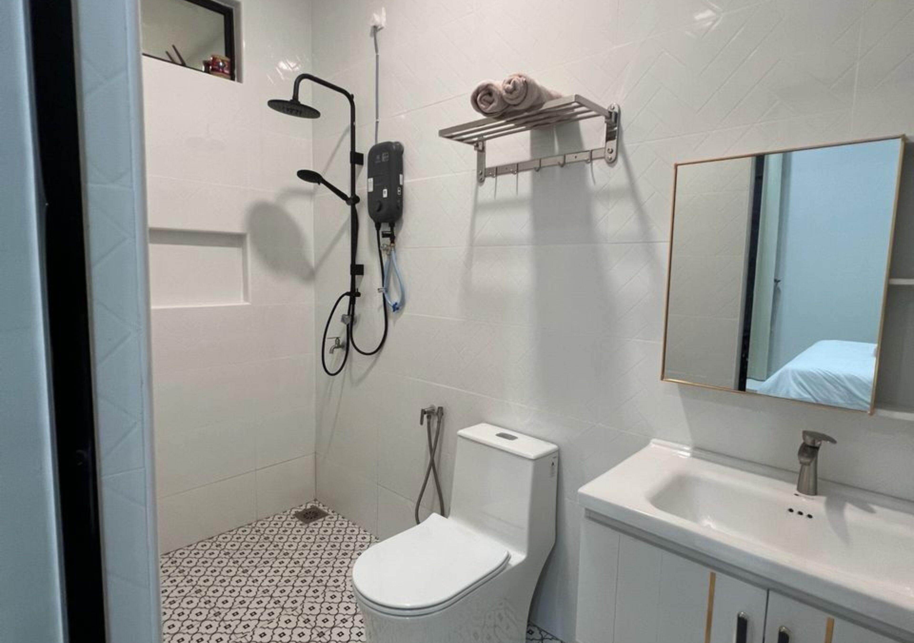 A bathroom with a toilet, sink, shower, and towel rack.
