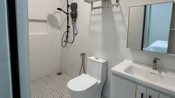 A bathroom with a toilet, sink, shower, and towel rack.