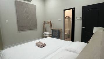 A hotel room with a bed, a wardrobe, a small seating area, and a door leading to a bathroom.