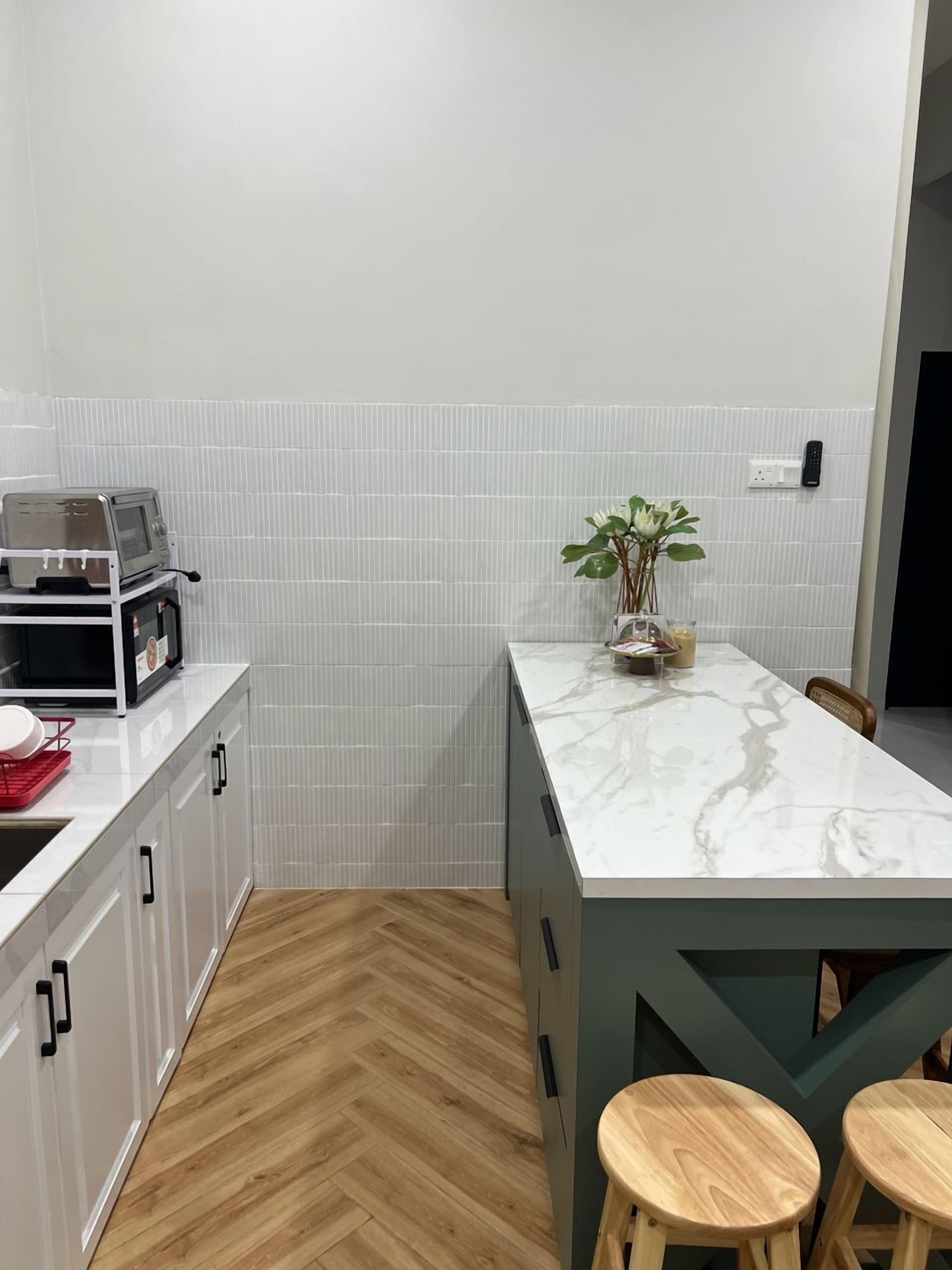 Eine moderne Küche mit weißen Schränken, einer Marmorarbeitsplatte, einem Toaster und einem Blumentopf.