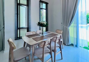 A dining area with a table, chairs, and a vase of flowers.