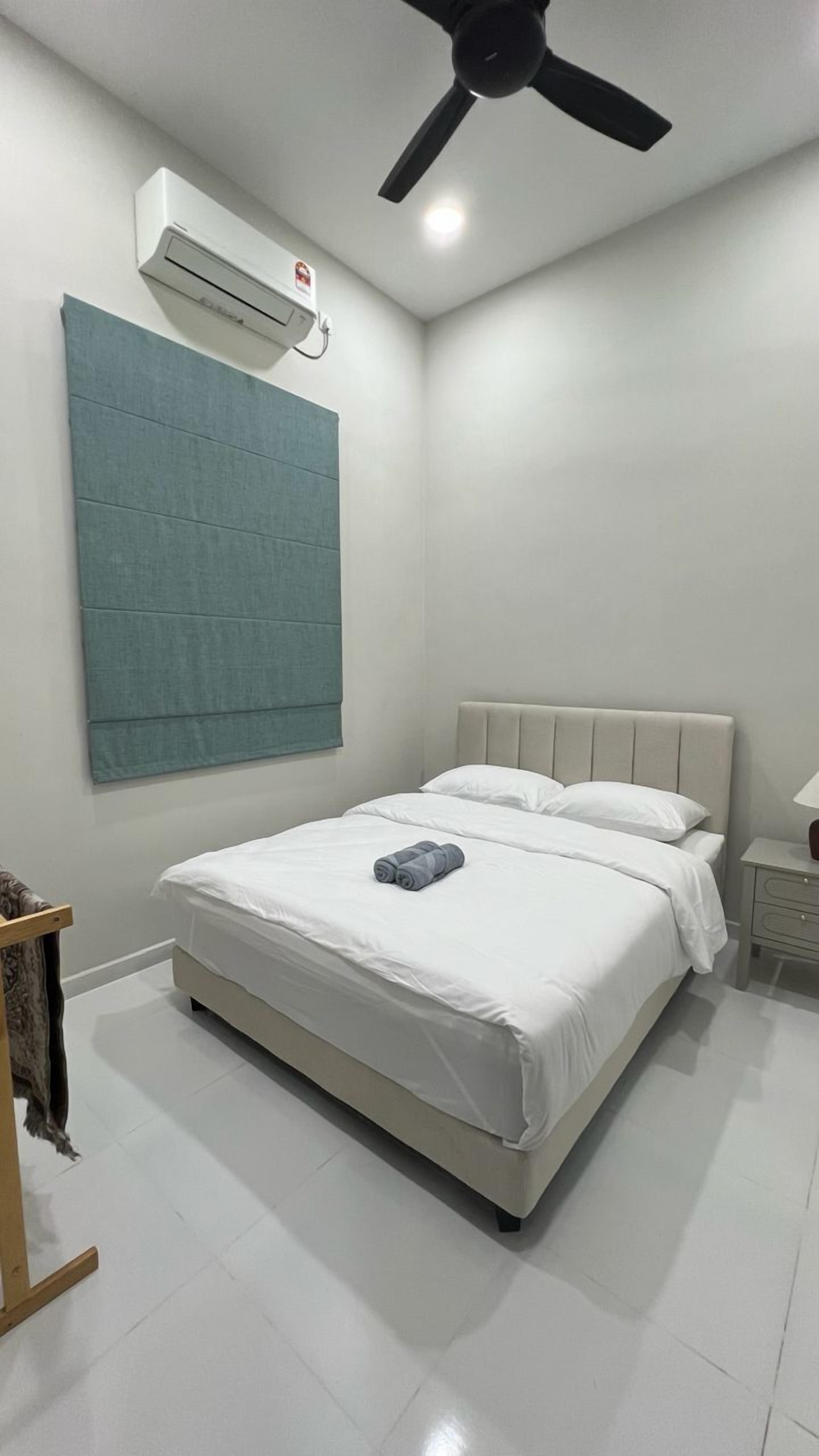 Un dormitorio con cama, ventilador de techo, aire acondicionado, mesita de noche y lámpara.