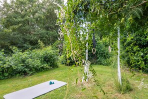 Ein Rasenbereich im Freien mit Yogamatte und Fitnessgeräten.