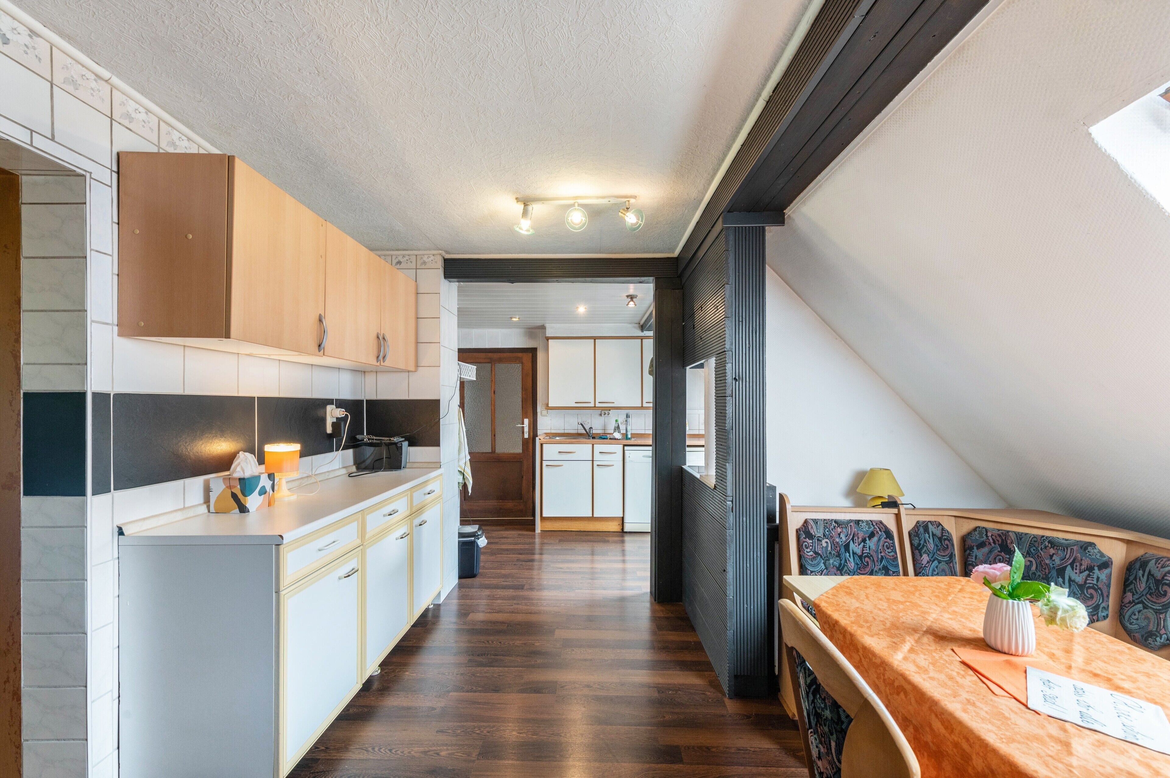 Une cuisine moderne avec des meubles en bois, un îlot central et un coin repas comprenant une table et des chaises.