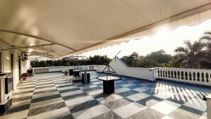 A rooftop terrace with a checkered floor, a covered area, and a railing.