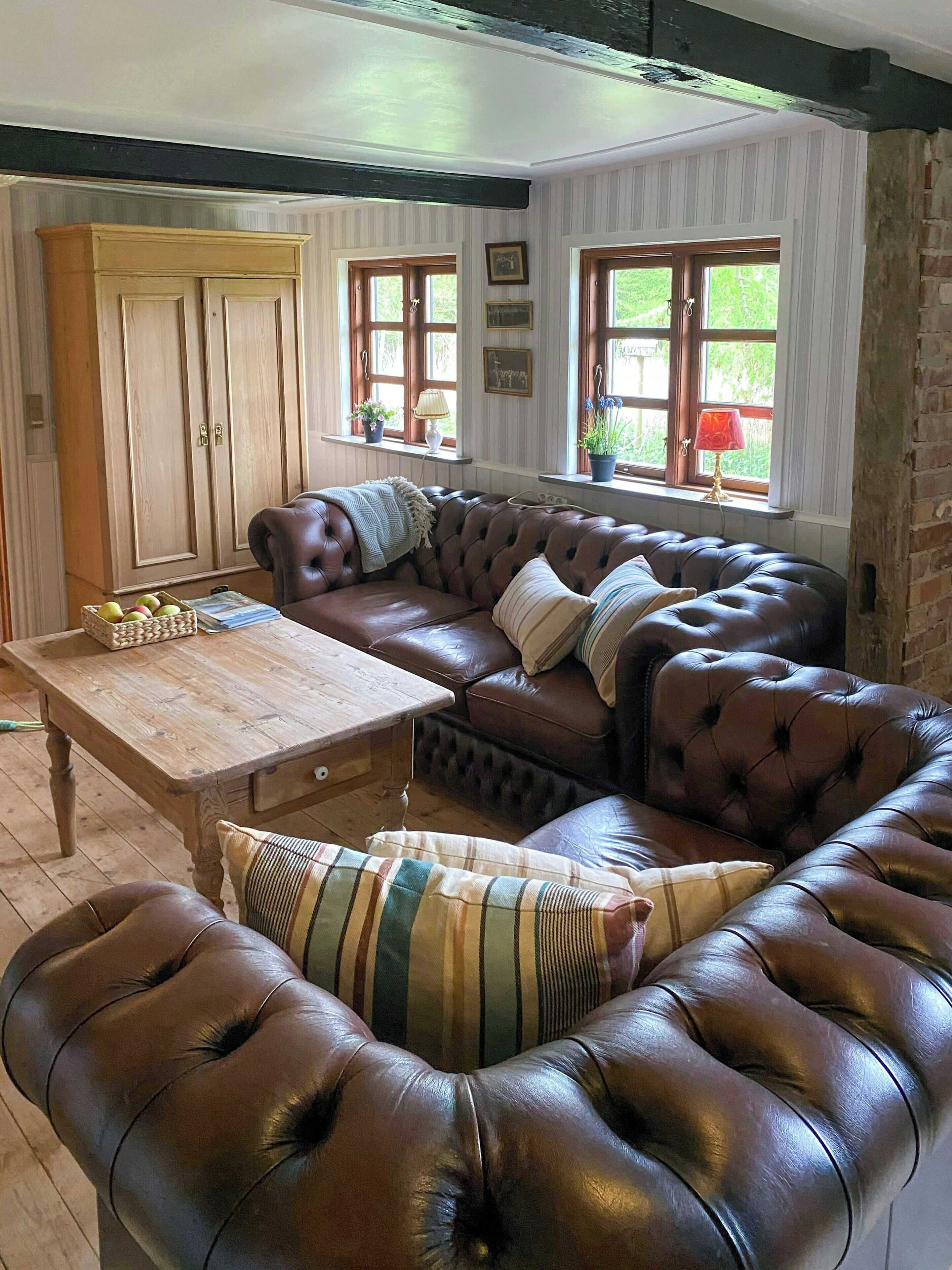 Een gezellige woonkamer met een leren bank, een houten salontafel en een grote kast.