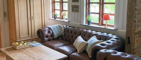 Een gezellige woonkamer met een leren bank, een houten salontafel en een grote kast.