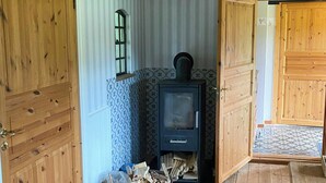 Una habitación acogedora con pisos de madera, chimenea, un cubo de leña y un banco.