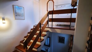 A multi-level wooden staircase with a handrail, a white wall with a framed picture, and a radiator on the right.
