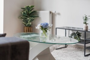 A modern living room with a glass-top coffee table, a potted plant, and a radiator in the background. - Stylish 2BR Wembley Stay |Sleeps 8| 5-Min Walk to Stadium (London)