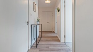 Ein Flur mit einer Leuchte, einem Konsolentisch mit Pflanze und einer Tür am Ende.