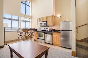 A compact kitchen with a dining table, chairs, a microwave, oven, dishwasher, and a refrigerator.