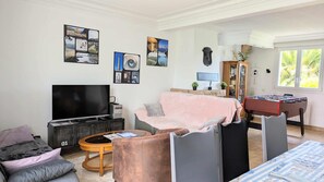 Ein Wohnzimmer mit Fernseher, Sofa, Couchtisch und Bildern an den Wänden.