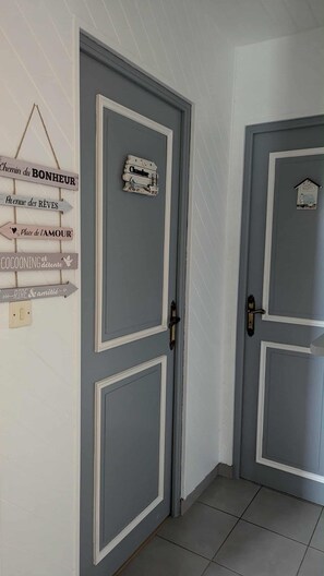 Ein Flur mit zwei grauen Türen, jede mit weißem Rahmen und einem kleinen Schild darüber.