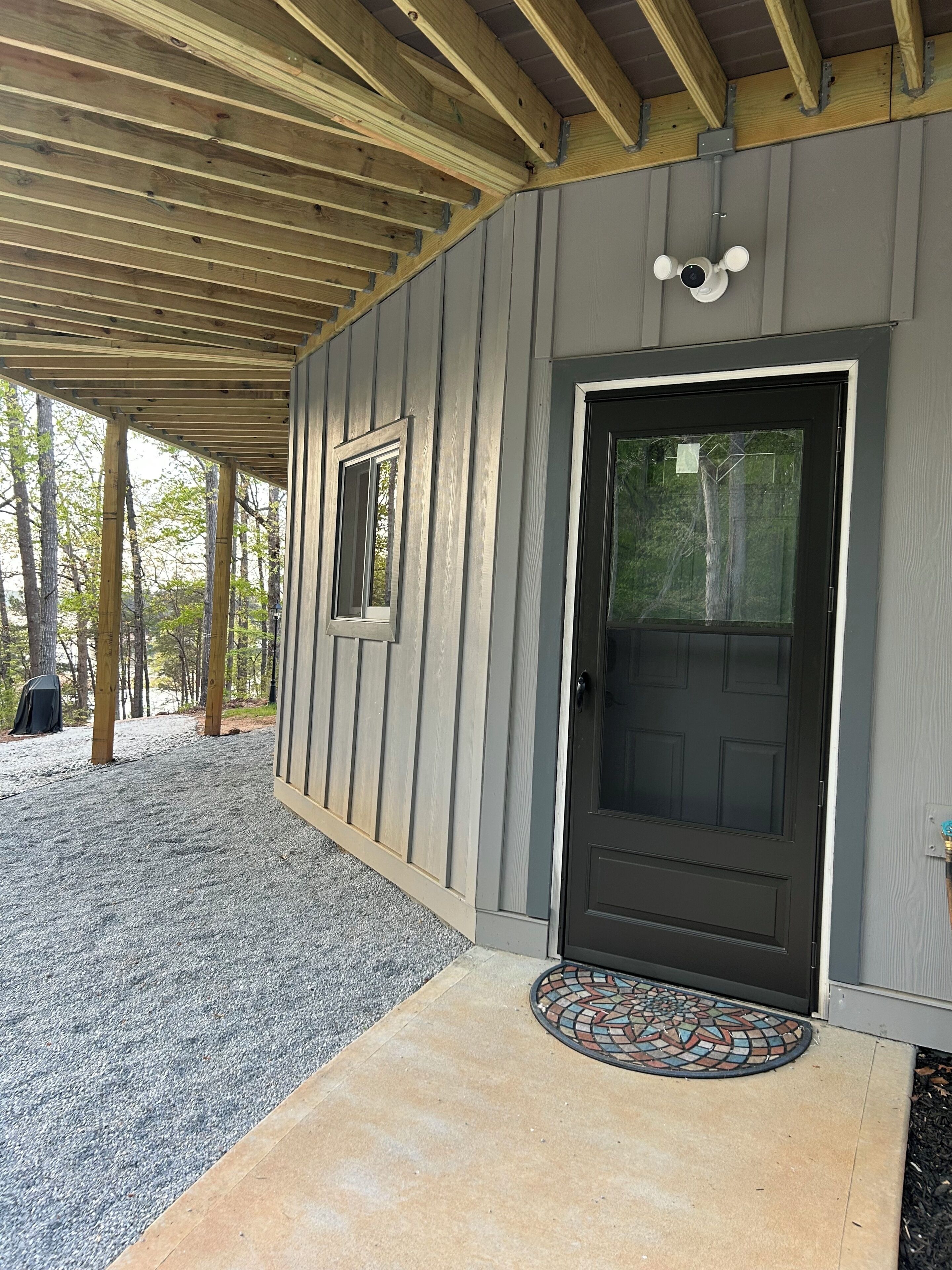 A covered porch with a black door, a small window, and a doormat.