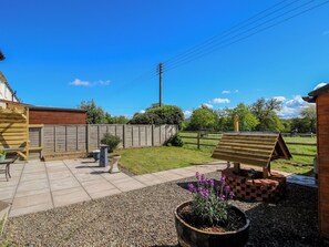 A patio area with a wooden bench, a small table, and a potted plant. - Onny Views (Craven Arms)
