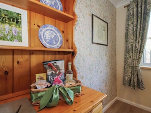 Une étagère en bois ornée d’assiettes décoratives, d’un tableau encadré et d’un panier en osier avec un ruban vert.
