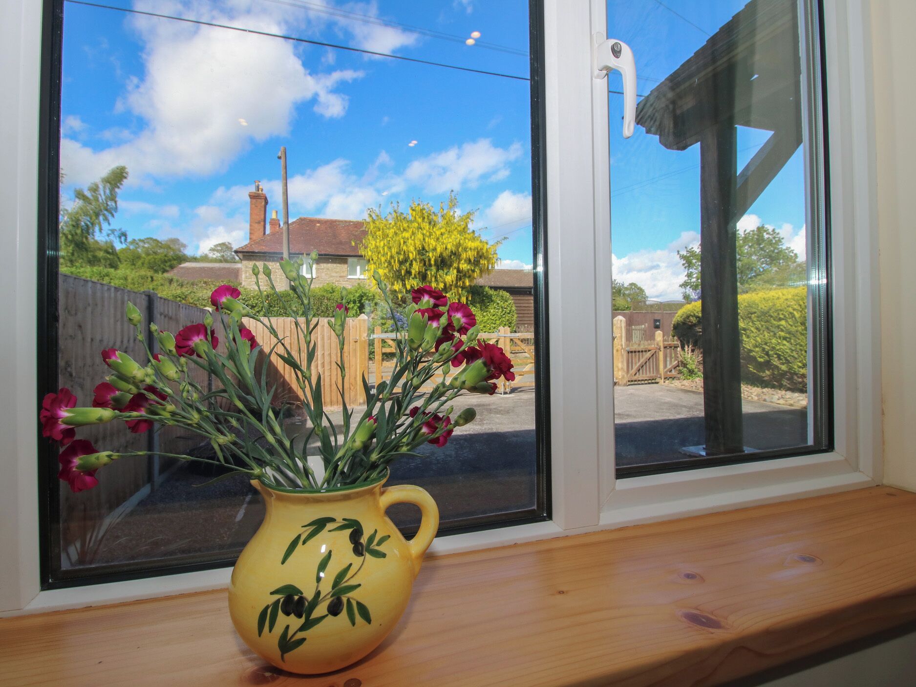 Eine gelbe Vase mit Blumen auf einem Fensterbrett.