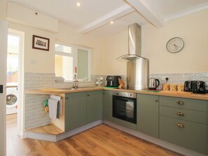 A kitchen with a stainless steel range hood, a built-in oven, and a window with a view. - Onny Views (Craven Arms)