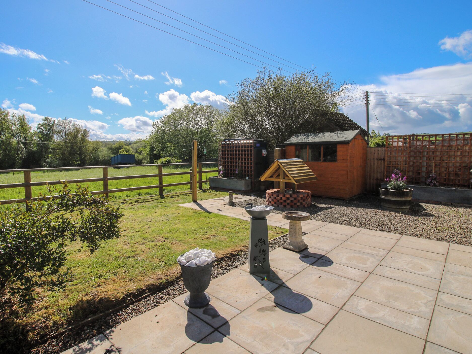 A patio area with a barbecue grill, outdoor seating, and a small shed.